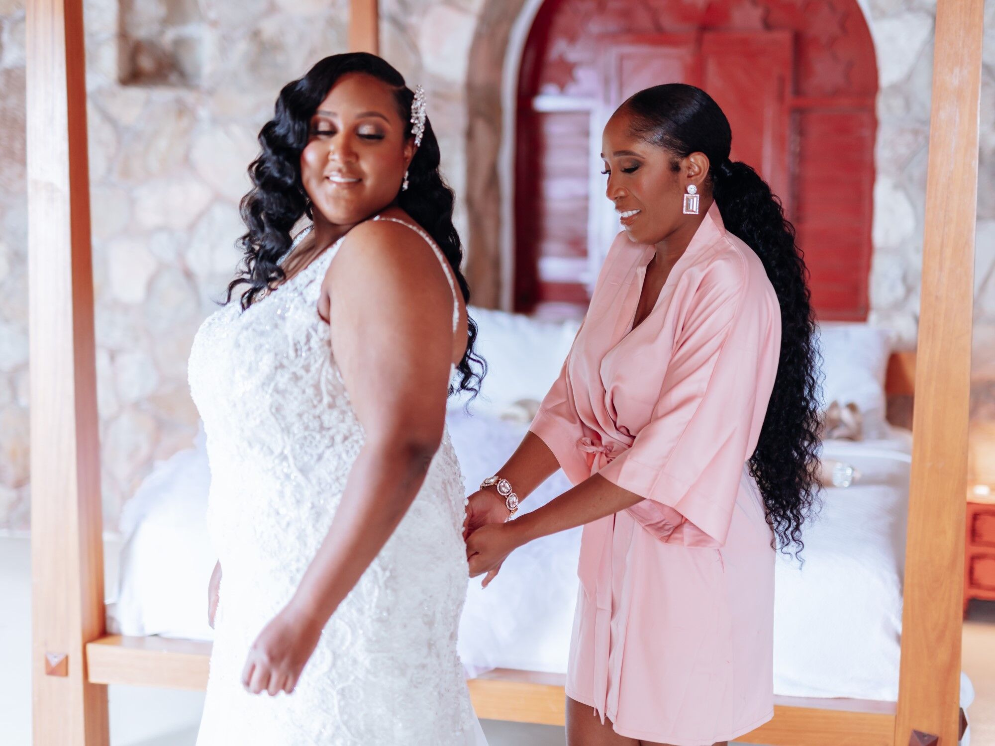 Bride getting ready with assistance from her maid of honor.