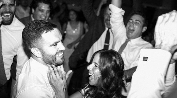 Couple laughing and celebrating on a crowded dance floor.