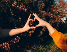 Couple making heart with hands during fall