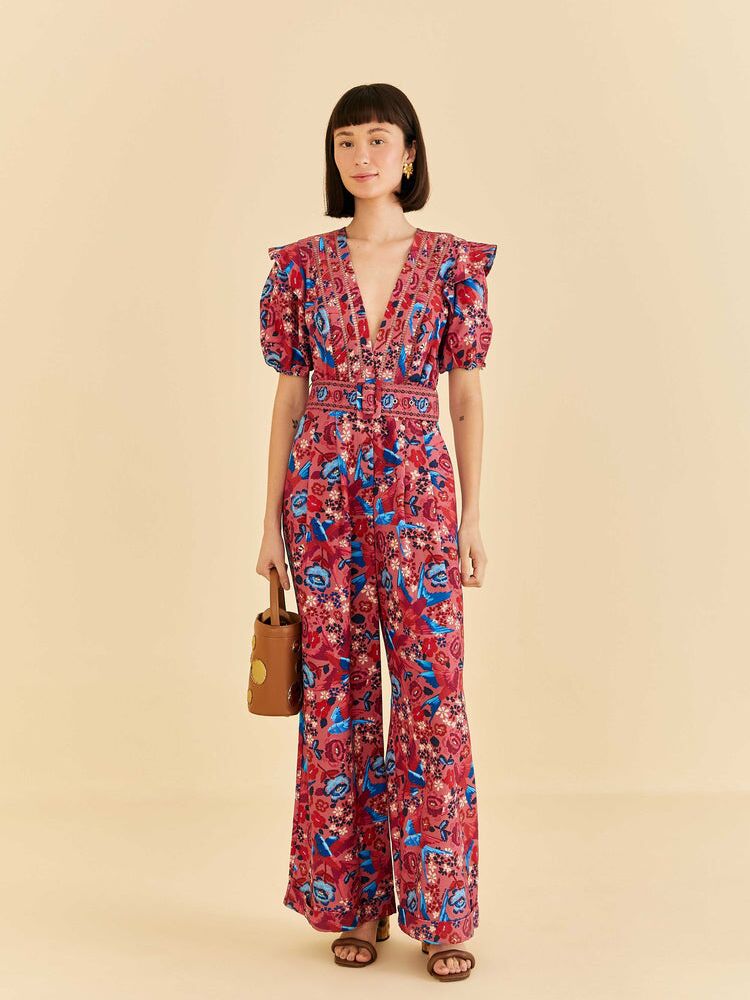 A red jumpsuit with puffed sleeves, flared shoulders, and a multicolor floral design from Farm Rio