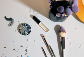 Table with makeup brushes, false lashes and sequins