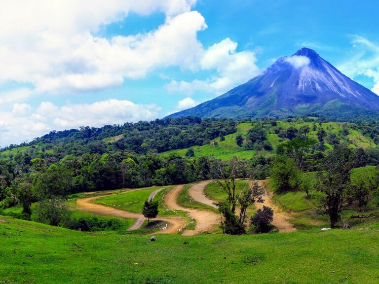 A volcano rises majestically into a blue sky in Costa Rica.