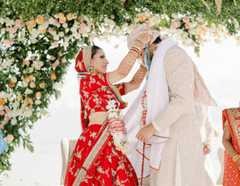 Bride placing mala around groom's neck at Hindu ceremony.