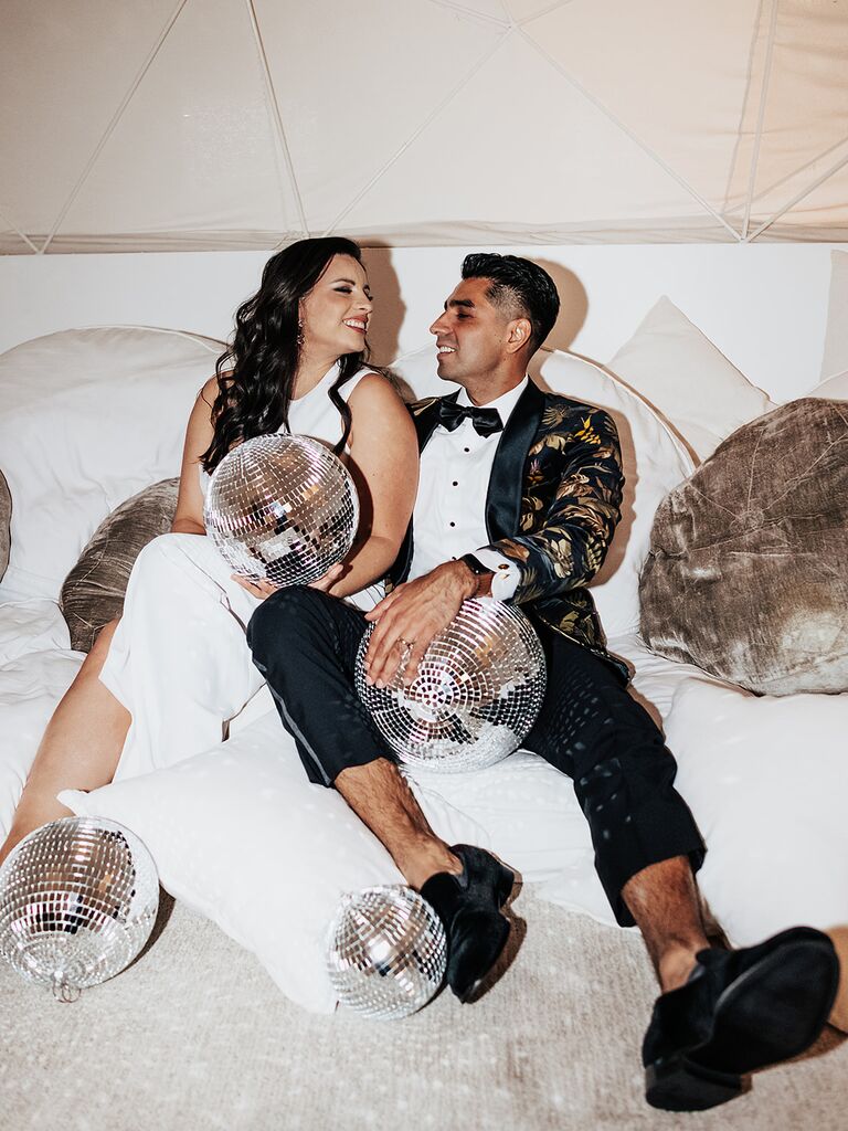 A happy couple gaze lovingly into each others eyes, surrounded by disco balls and soft cushions.