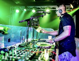 DJ working the booth at an event with uplighting