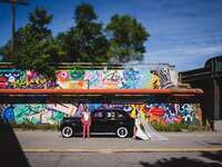 couple standing in front of a vintage car and a colorful graffiti wall 