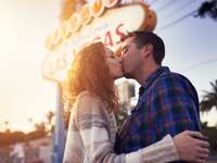 A couple kiss outside of the famous Las Vegas sign