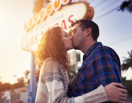 A couple kiss outside of the famous Las Vegas sign