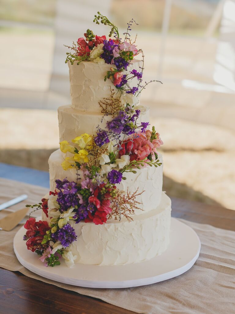 four tier textured buttercream wedding cake with pink, purple and yellow wildflowers
