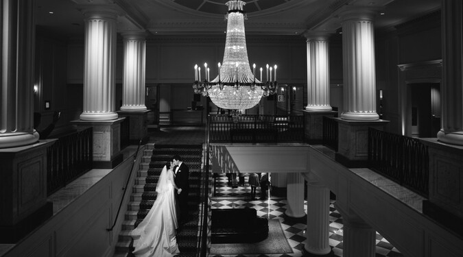 Bride and groom on grand staircase under chandelier at InterContinental New York