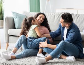 Couple sitting on floor and laughing with daughter