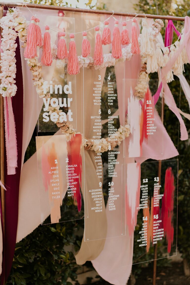 Acrylic seating chart hanging amongst boho pink decorations