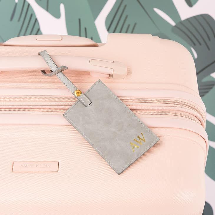 Gray leather luggage tag with engraved gold initials