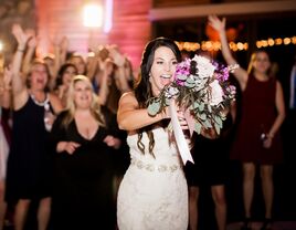 bride tossing bouquet at wedding reception