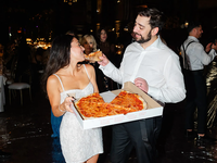 Groom feeding bride pizza at wedding reception