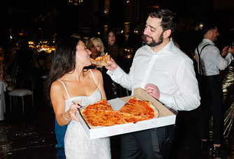 Groom feeding bride pizza at wedding reception