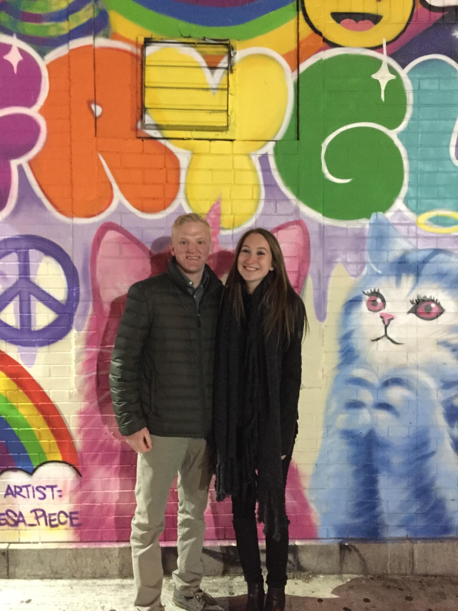 A few weeks later, as Christopher went home to Long Island and Sasha back to Westchester for Thanksgiving break, Christopher asked Sasha to meet halfway in NYC for a date night.  They grabbed a sushi dinner, went to a UCB comedy show and grabbed hot chocolate to extend the night.  Before departing, they took a quick photo in front of a mural and Christopher walked Sasha to Grand Central to take her train home.  Sitting in the lower level together at 12AM waiting for Sasha's train to arrive, Christopher formally asked her to be his girlfriend.