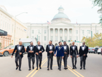 Groomsmen and groom walking down street in classic black tuxedos