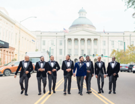 Groomsmen and groom walking down street in classic black tuxedos