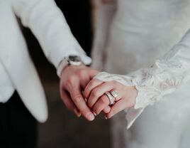 Couple holding hands with bride wearing engagement and wedding ring