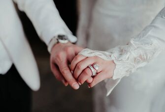 Couple holding hands with bride wearing engagement and wedding ring