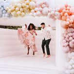 Bride and groom jumping in bouncy castle during welcome party