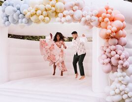 Bride and groom jumping in bouncy castle during welcome party