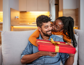 Wife giving husband a present and kiss on the cheek