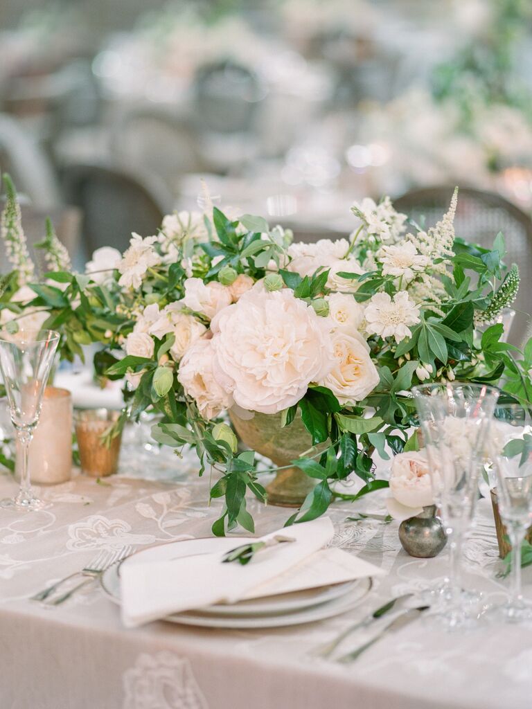 elegant spring wedding centerpiece with white garden roses and ivory flowers in small stone urn vase