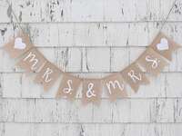 Mrs. & Mrs. on burlap pennants in simple white script with hearts at beginning and end