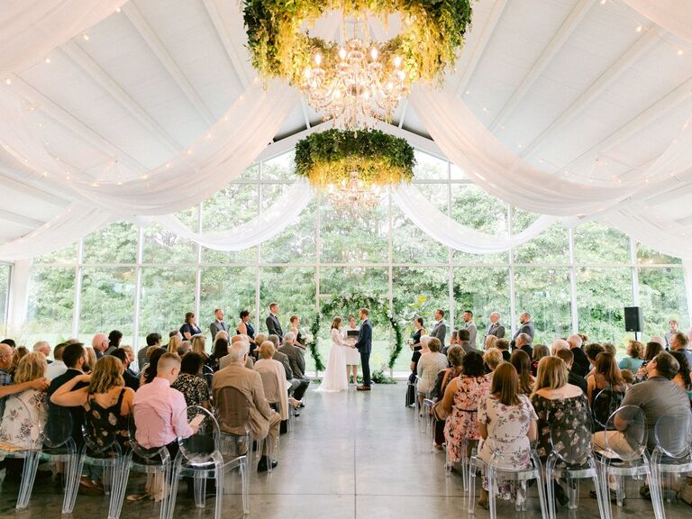 Couple exchanging their vows in the indoor ceremony site with floor-to-ceiling windows