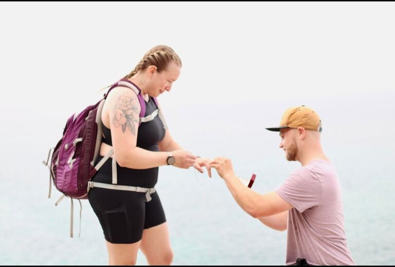 Allison and Kyle celebrating as they get engaged during an 11 mile hike with family and friends!