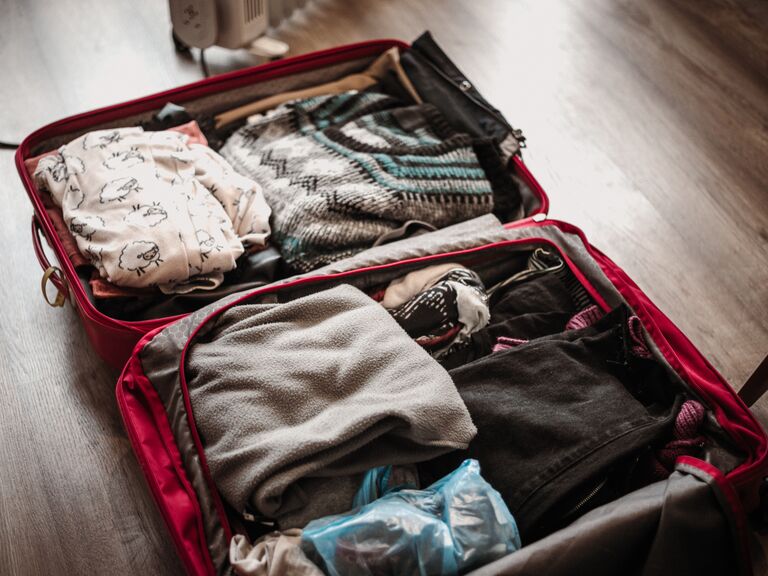 Open suitcase packed with winter clothes