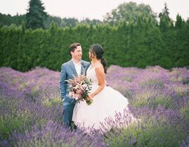 Bride and groom in lavender field with bouquet of purple wedding flowers