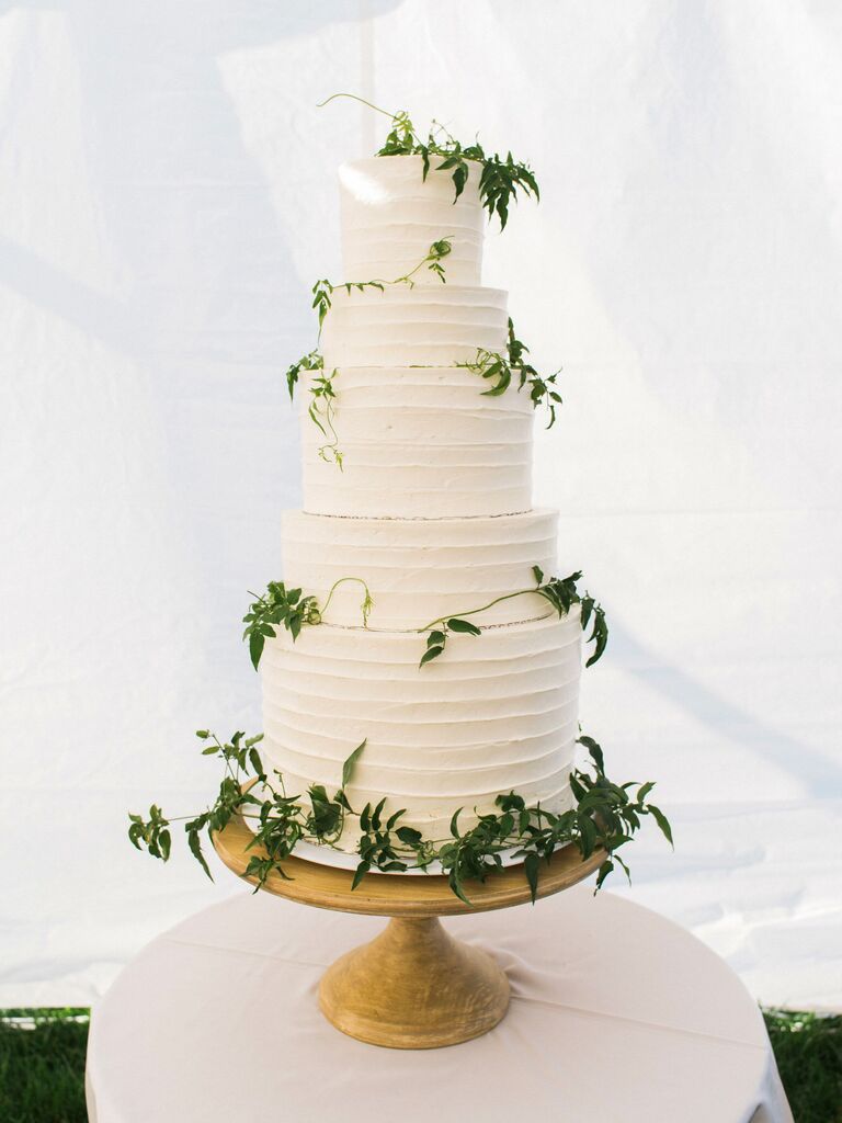 five tier white buttercream wedding cake decorated with ivy vines wrapped around the cake