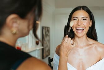 Bride smiling while getting her makeup done