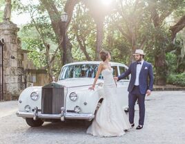 Newlyweds pose in front of a vintage car, with ancient oaks in the backround.