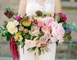 bride holding oversized wedding bouquet with pale pink roses, peonies, yellow roses, and eucalyptus