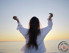 woman standing alone with arms up outside