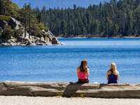 two women sitting on the shore of lake tahoe