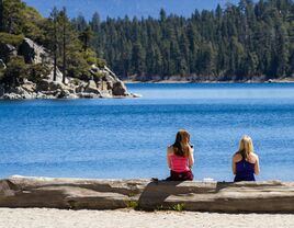 two women sitting on the shore of lake tahoe