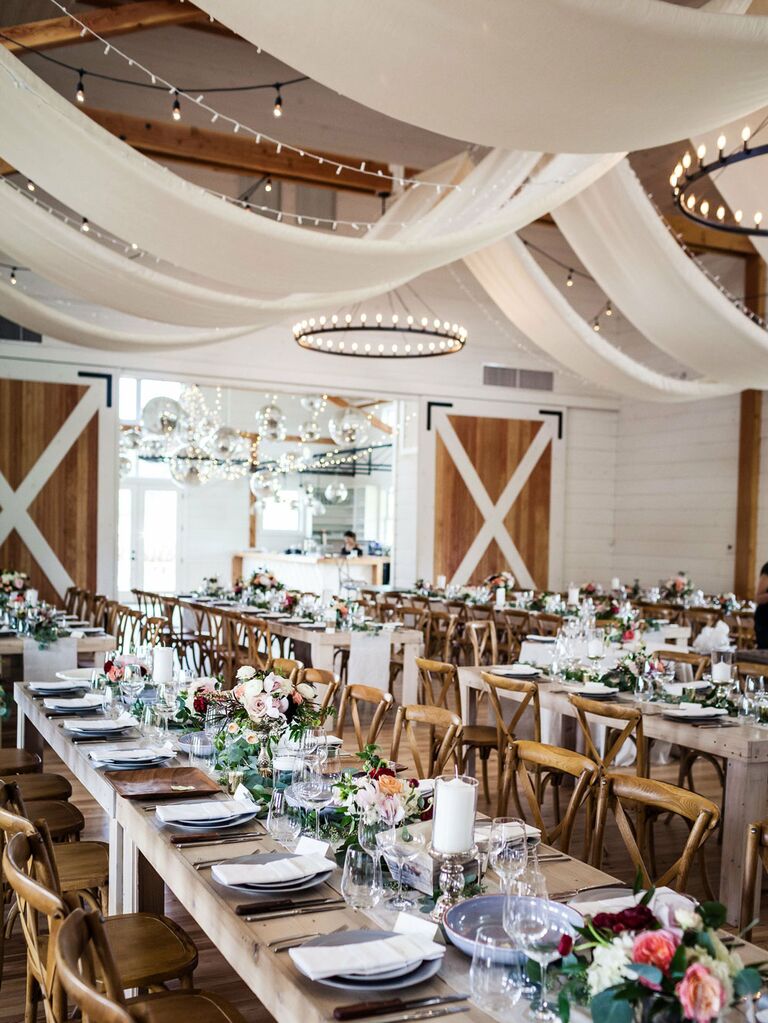 Romantic barn wedding venue with white fabric draped across ceilings