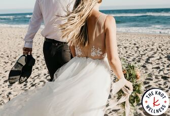 Bride and groom walking on beach on wedding day