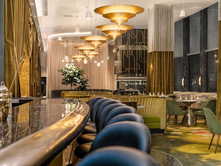 animae restaurant bar wraparound against gold glimmering pendant lights and a pretty velvet green dining room romantic for couples