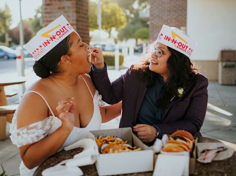 Couple feeds each other french fries outside an In-N-Out. 