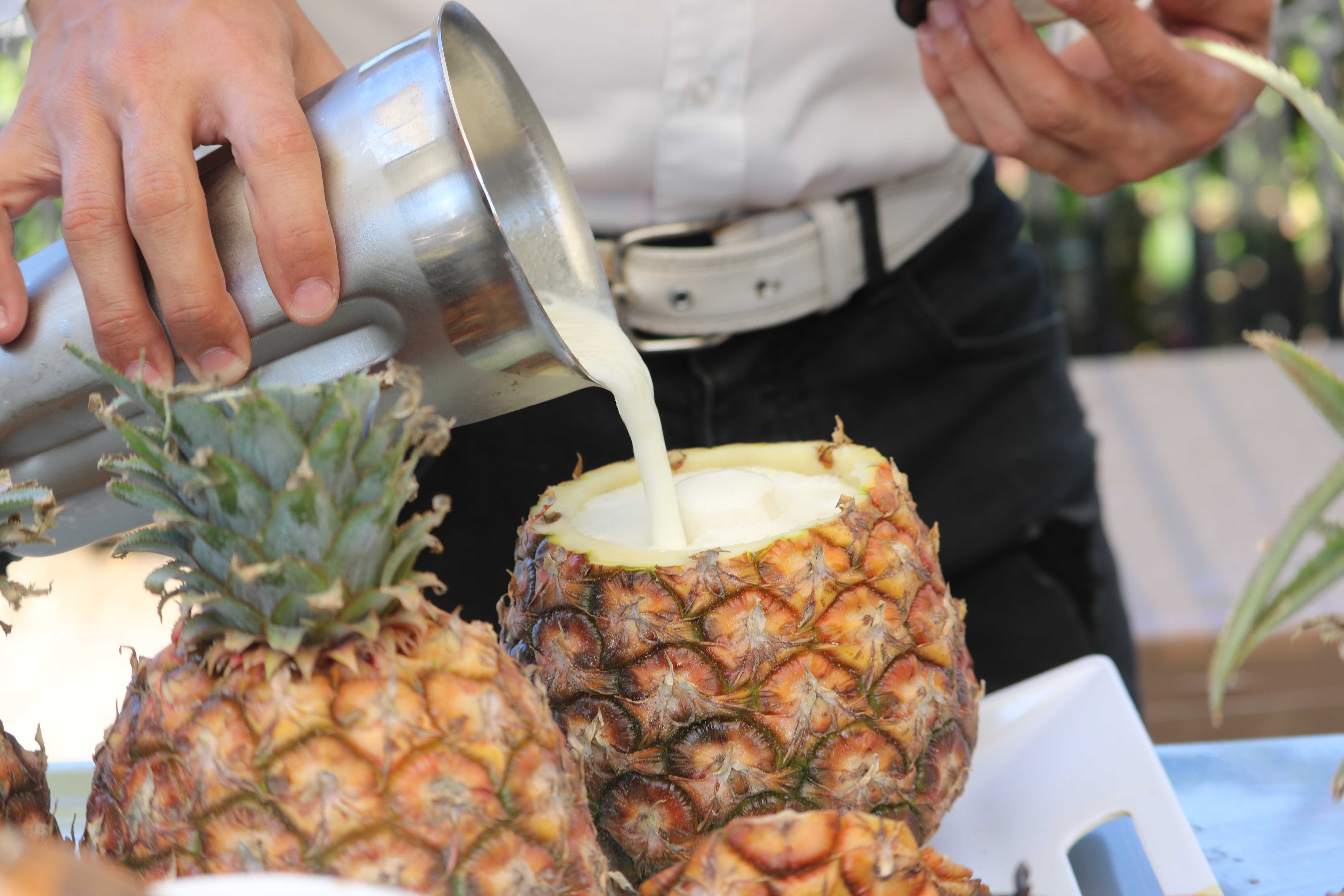 Bartender pouring a cocktail into a pineapple