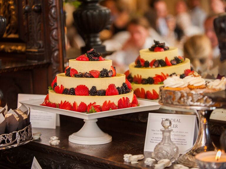 Three-tiered cheesecake displayed on a dessert table. 