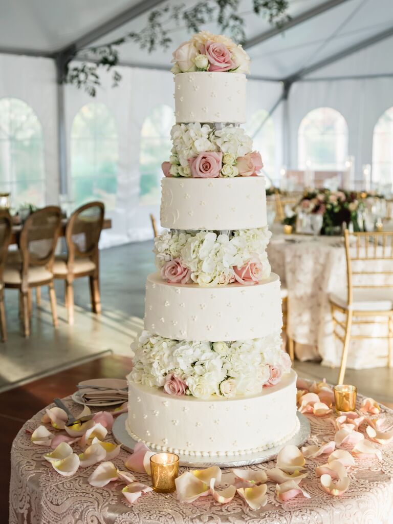 four tier buttercream wedding cake with white hydrangeas and pink roses in between each tier