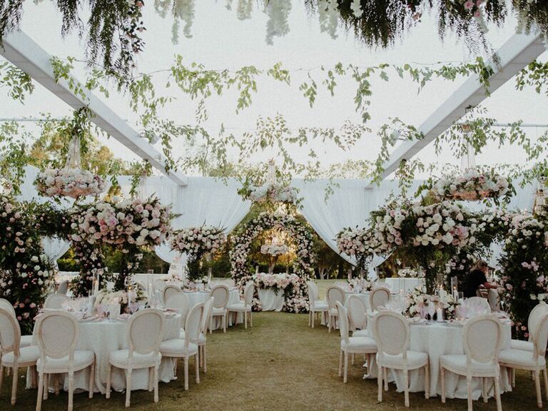 a tented wedding with lush greenery and tall pink and green centerpieces
