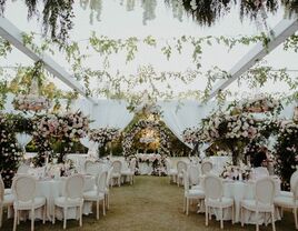 a tented wedding with lush greenery and tall pink and green centerpieces